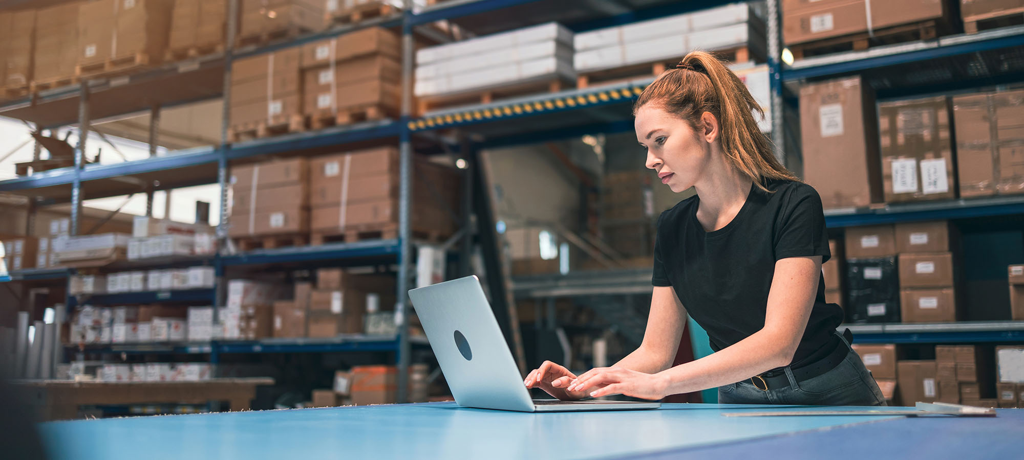 A woman in a warehouse managing inventory using a laptop, representing efficient stock handling for Yankee